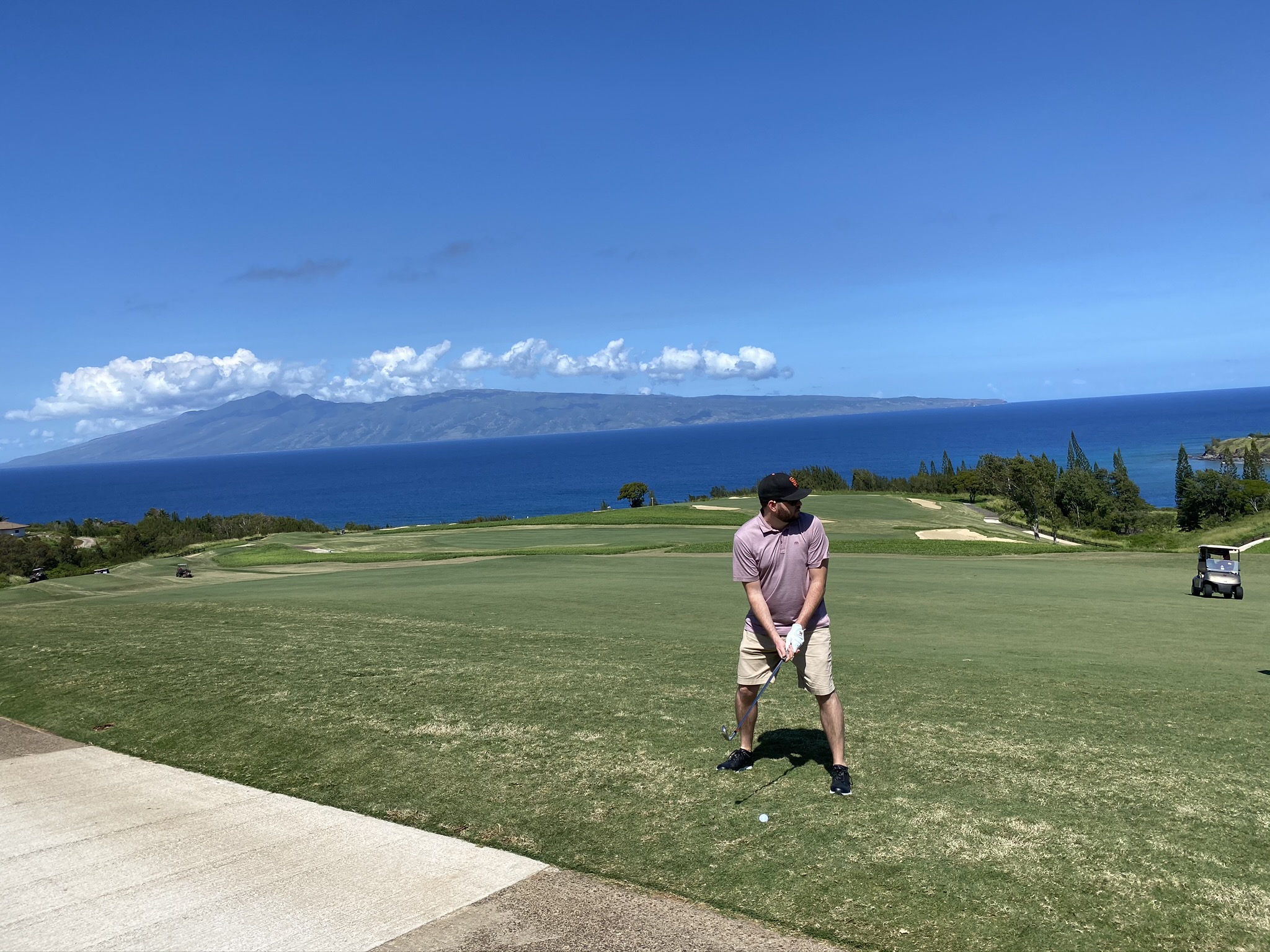 preparing to hit a shot with ocean and molokai island in background